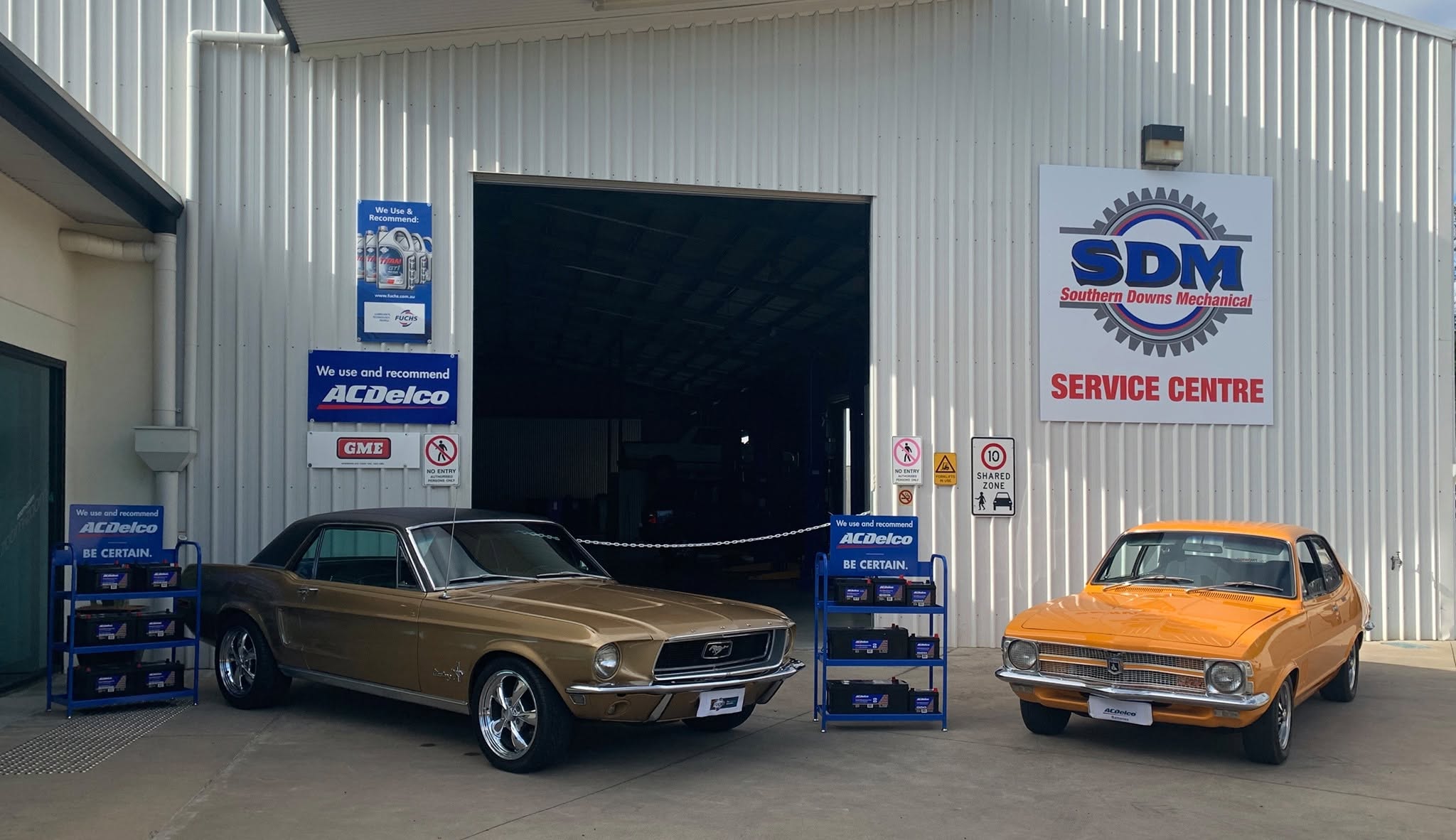 The Southern Downs Mechanical workshop in Warwick with a gold Ford Mustang and an orange Holden Torana parked outside the open roller door